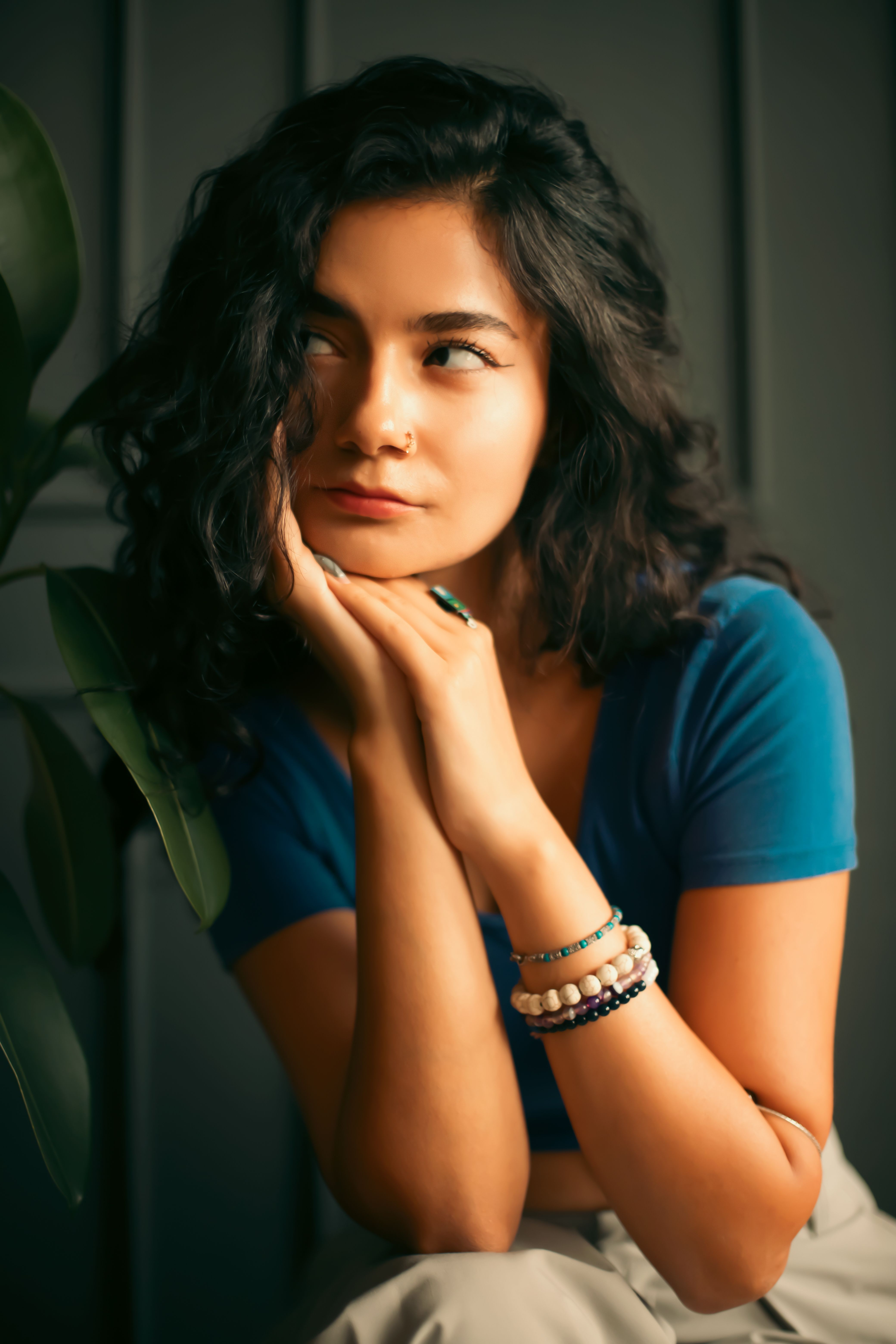 Portrait of a thoughtful woman with curly hair sitting indoors, exuding calmness.