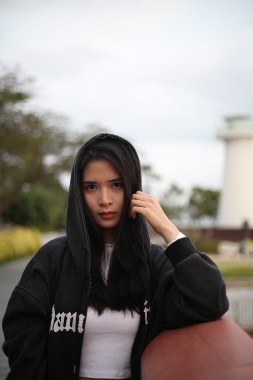 Young Woman Wearing a Hoodie Standing Outside 