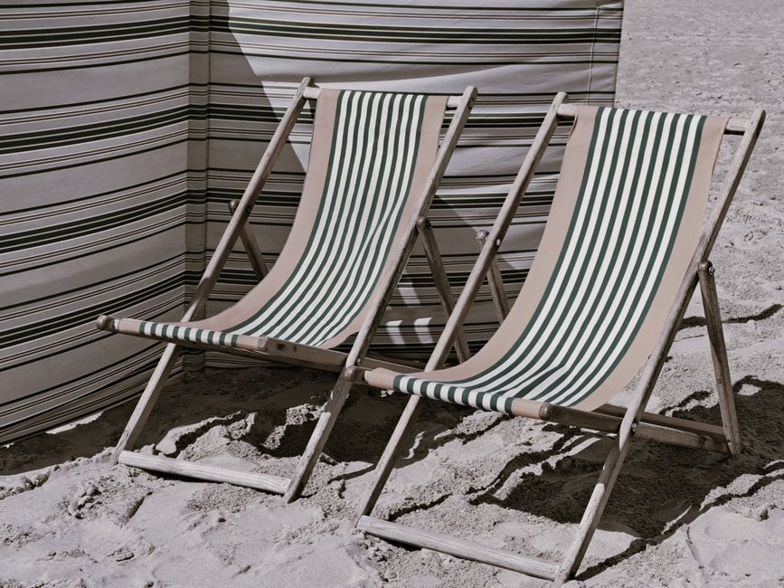 Pair of striped deckchairs on a sandy beach, perfect for summer relaxation.