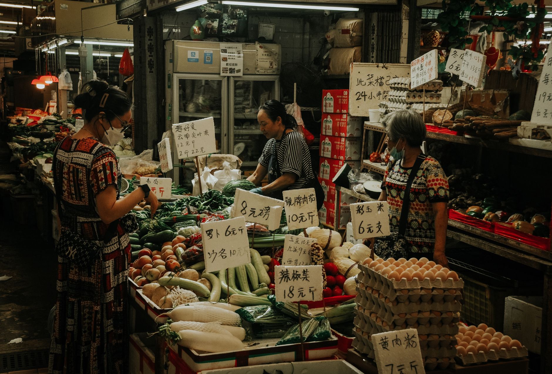 留學生省錢吃法:旅行鍋一週簡單菜單,每餐不到50元 A lively market scene with women shopping for fresh veggies and eggs.