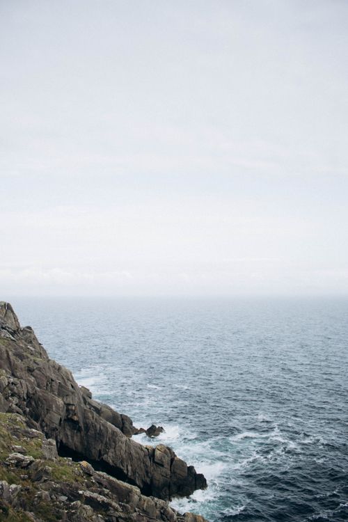 Free Peaceful ocean scene with rocky cliffs and clear sky. Stock Photo