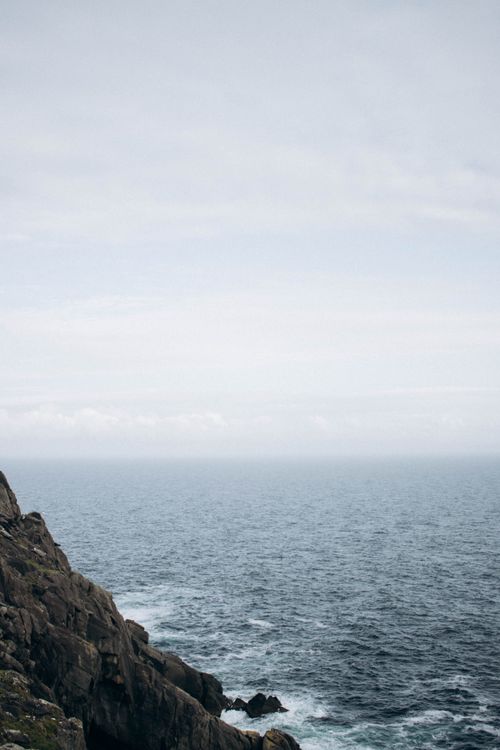 Free Serene image of a vast ocean under an overcast sky, featuring a rocky coastline. Stock Photo