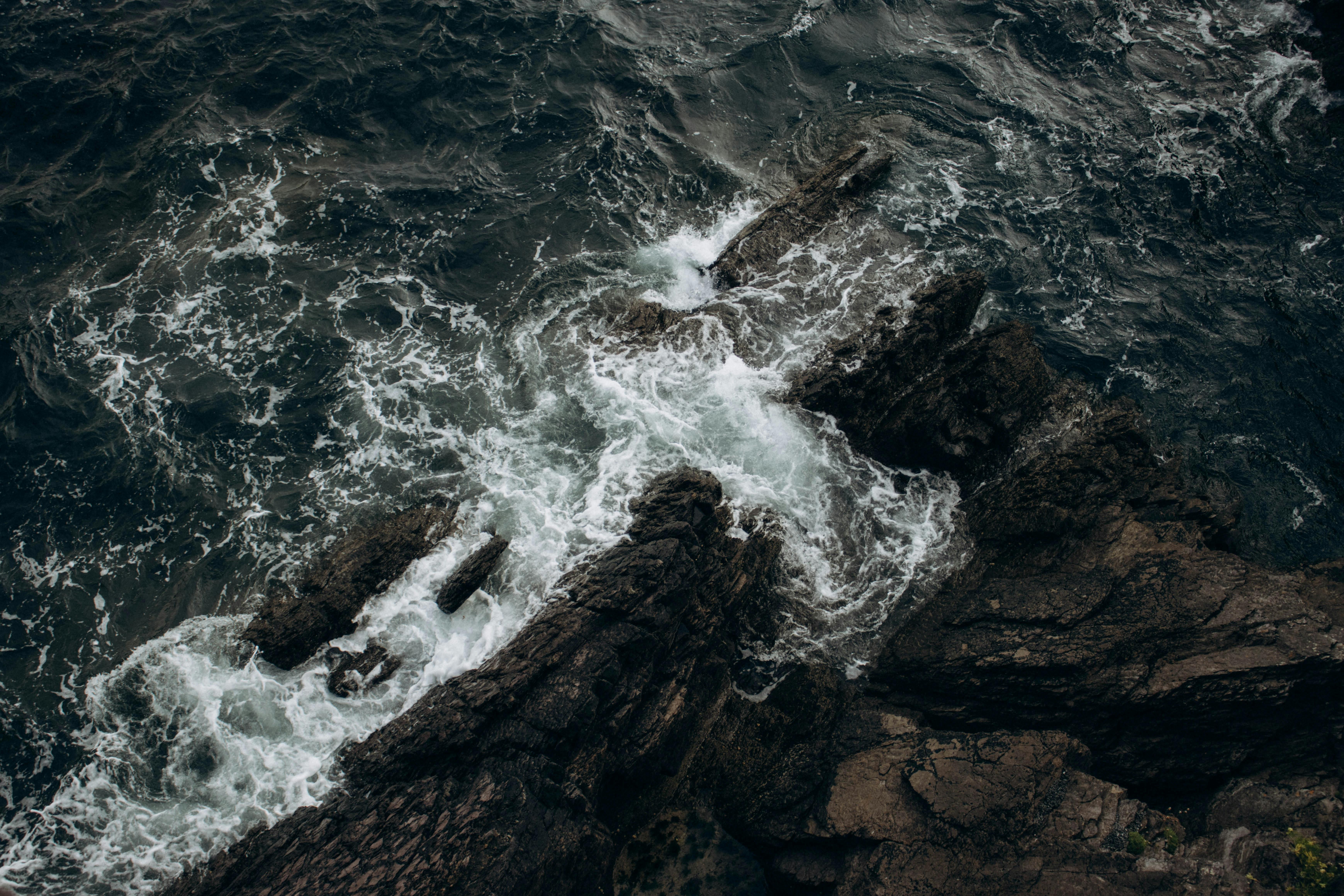 Aerial view of ocean waves crashing against rugged rocky coast, showcasing nature's power.
