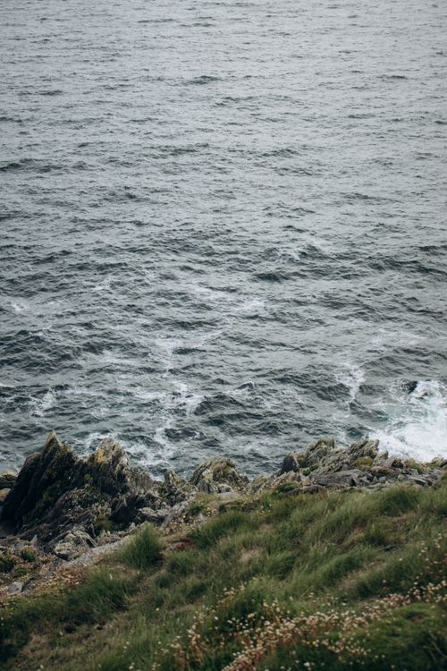 Free A scenic view of the ocean waves gently hitting a rocky shoreline, captured outdoors. Stock Photo