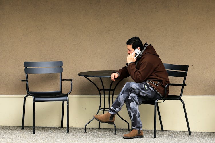 Man Sitting By The Table Talking On A Phone