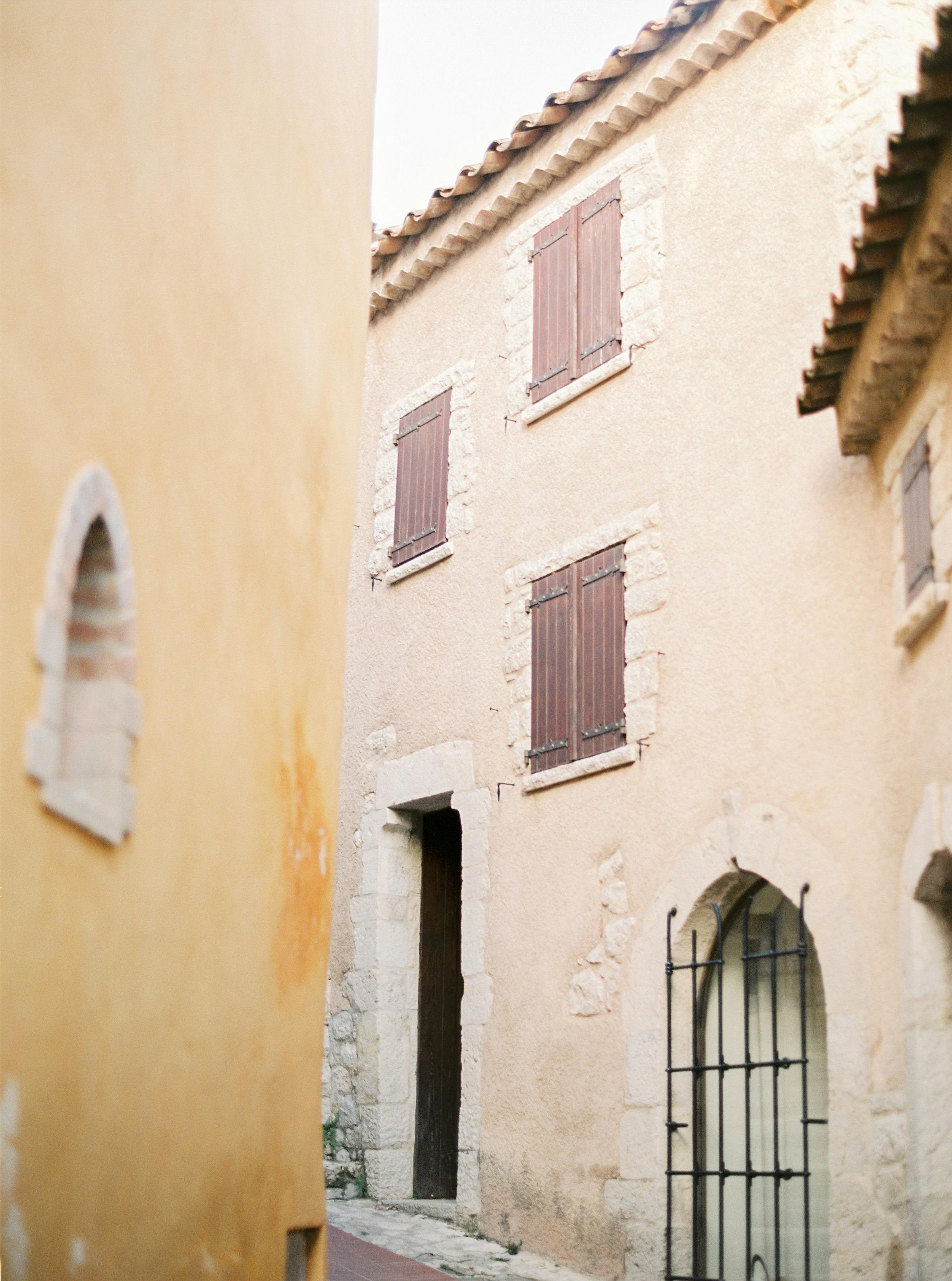 Charming European street with rustic stone architecture and closed shutters.