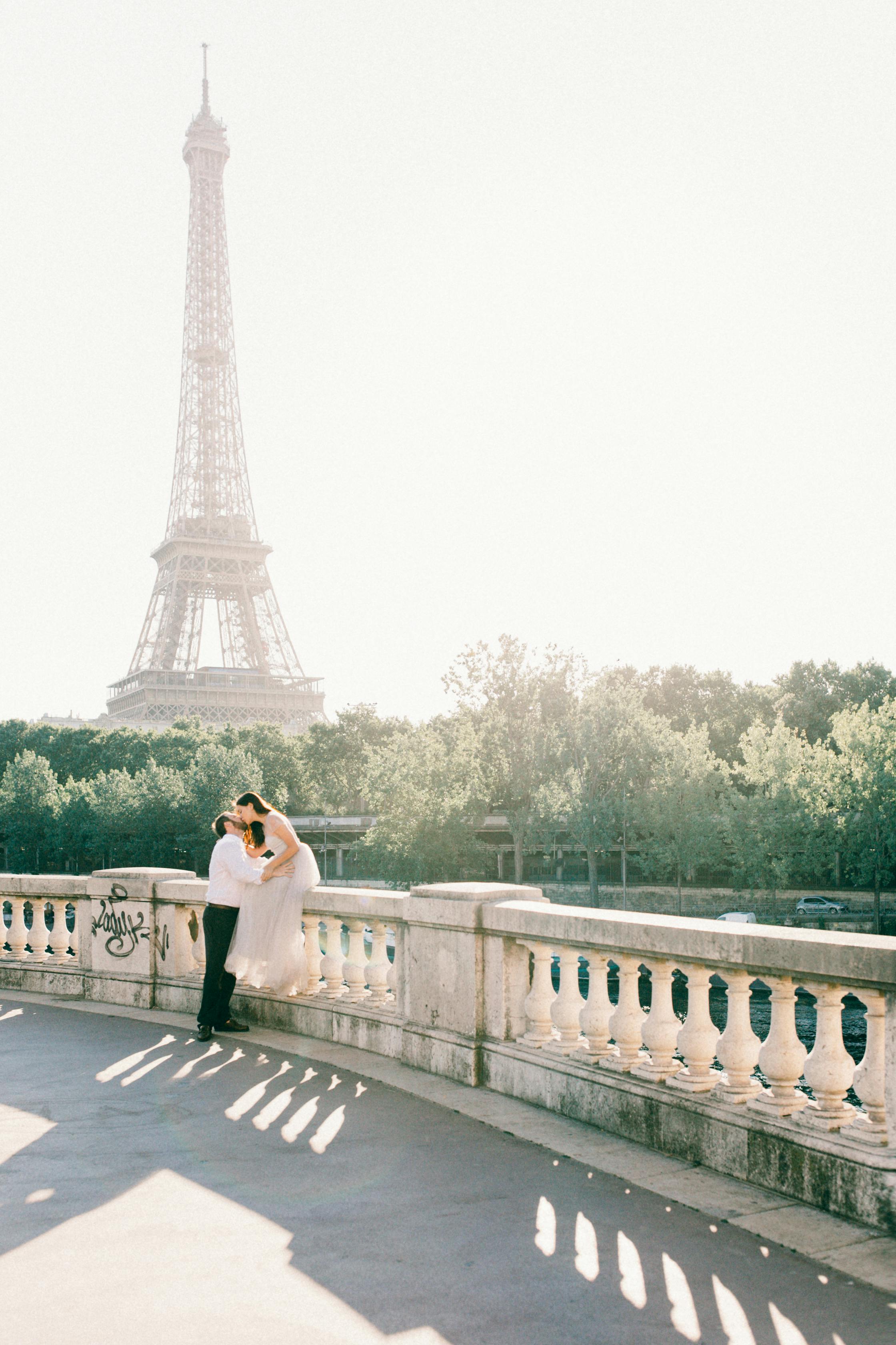 couple kissing on bridge overlooking eiffel tower in paris france