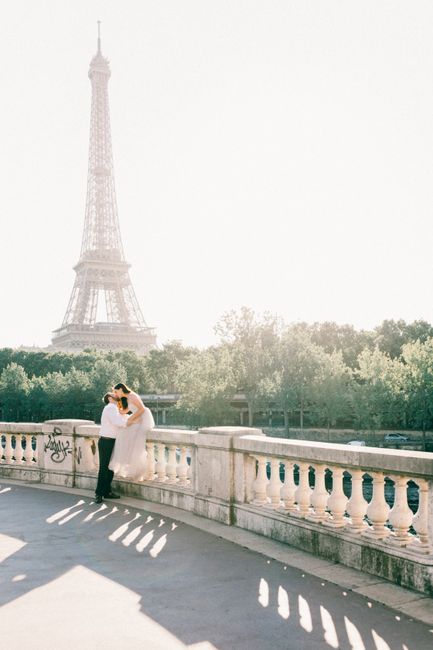 A couple embraces on a bridge with the iconic Eiffel Tower in the background, embodying romance in Paris.
