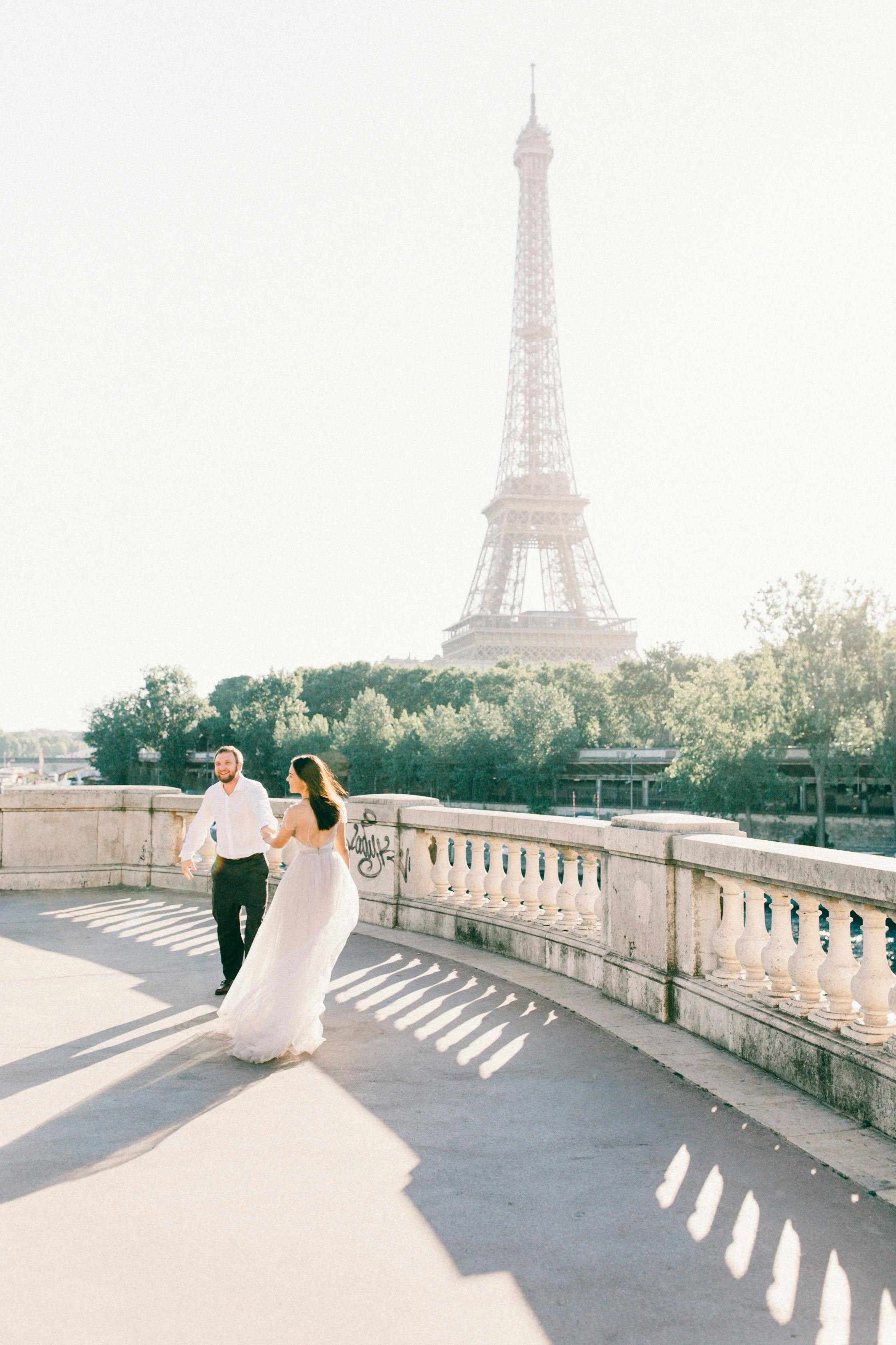A newlywed couple joyfully poses near the iconic Eiffel Tower in Paris.