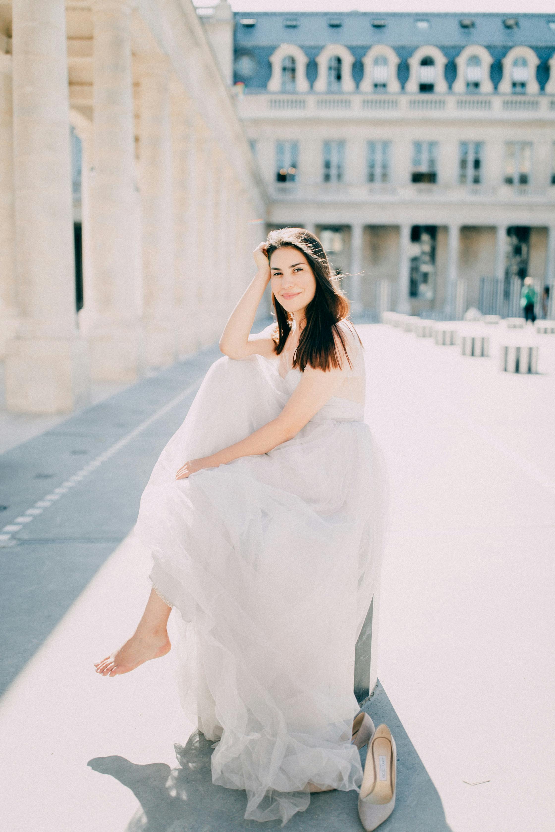 bride sitting barefoot on square in front of louvre paris france