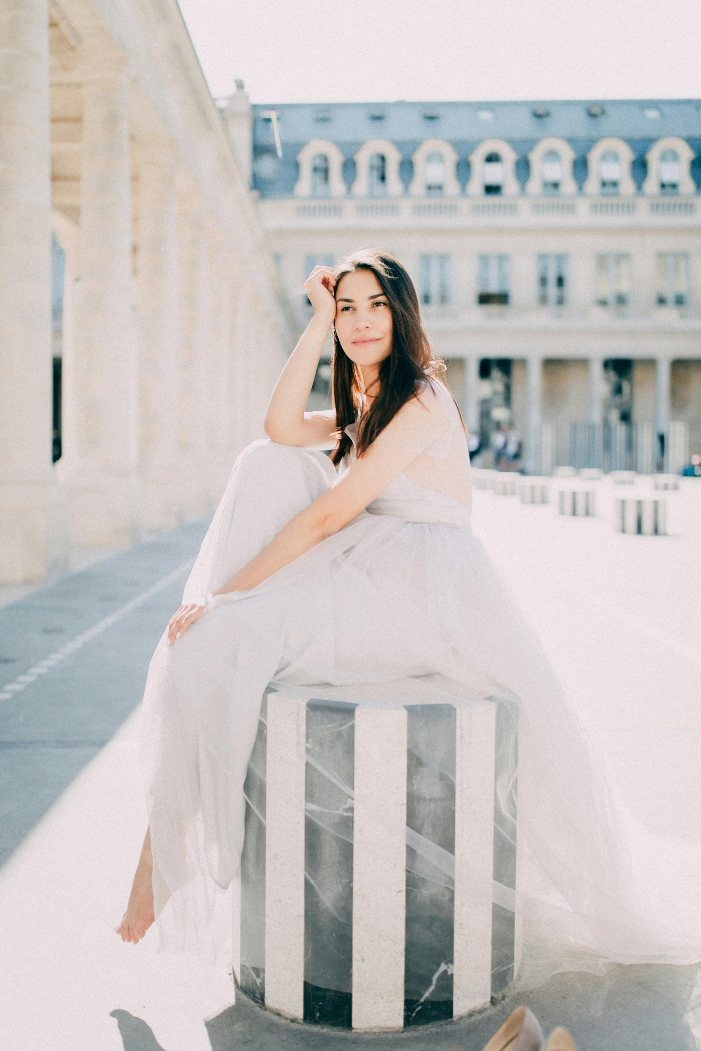 Bride in white dress sitting at Palais Royal, Paris. Elegant and serene.