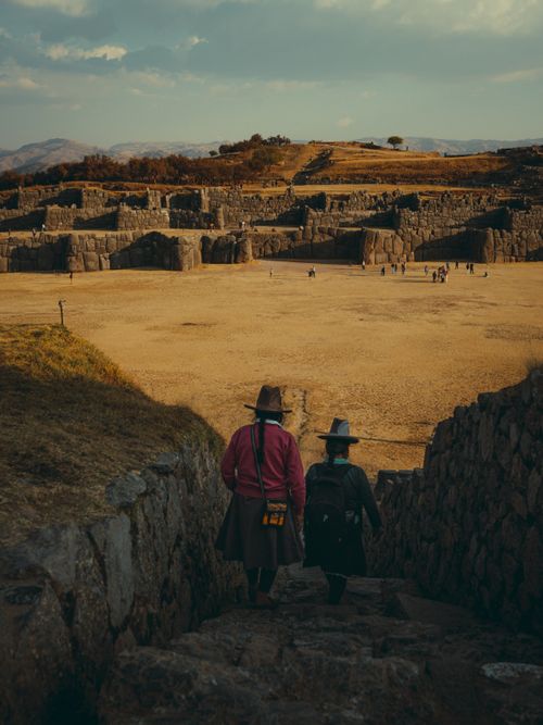 Free Tourists dressed in traditional attire walk through the ancient Sacsayhuamán ruins near Cusco, Peru. Stock Photo