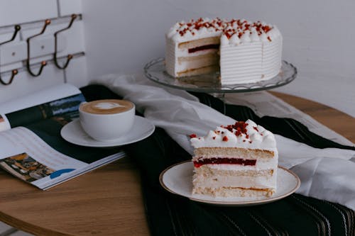 Piece of Sponge Cake with Jelly and Cranberries on a Table Next to a Cap of Coffee
