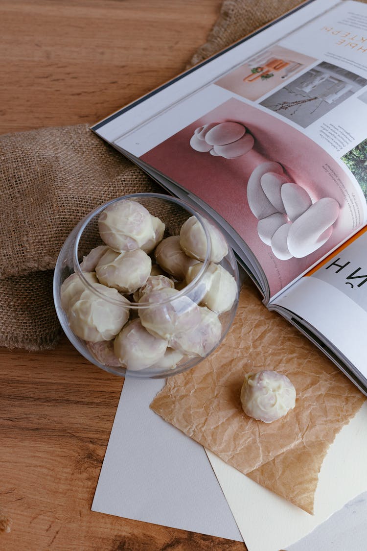 White Chocolate Covered Cookies In Glass Bowl Next To Open Magazine