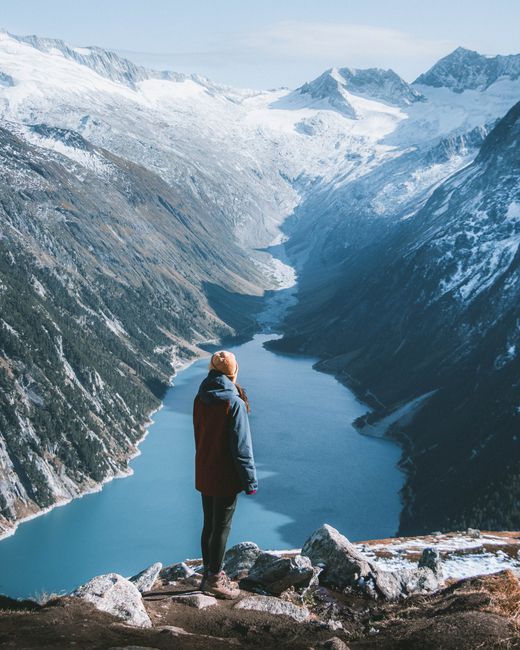A woman enjoys the stunning view of a snowy mountain lake in Austria.