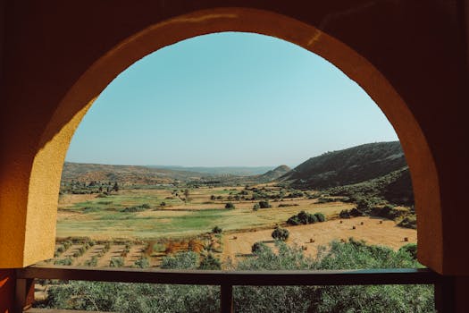A beautiful view of a rural valley surrounded by hills, seen through a Mediterranean-style archway.