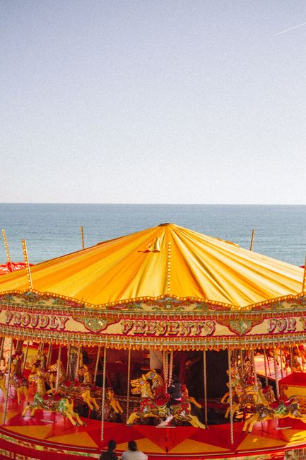 Colorful carousel by the seaside offers a joyful carnival experience under a bright summer sky.