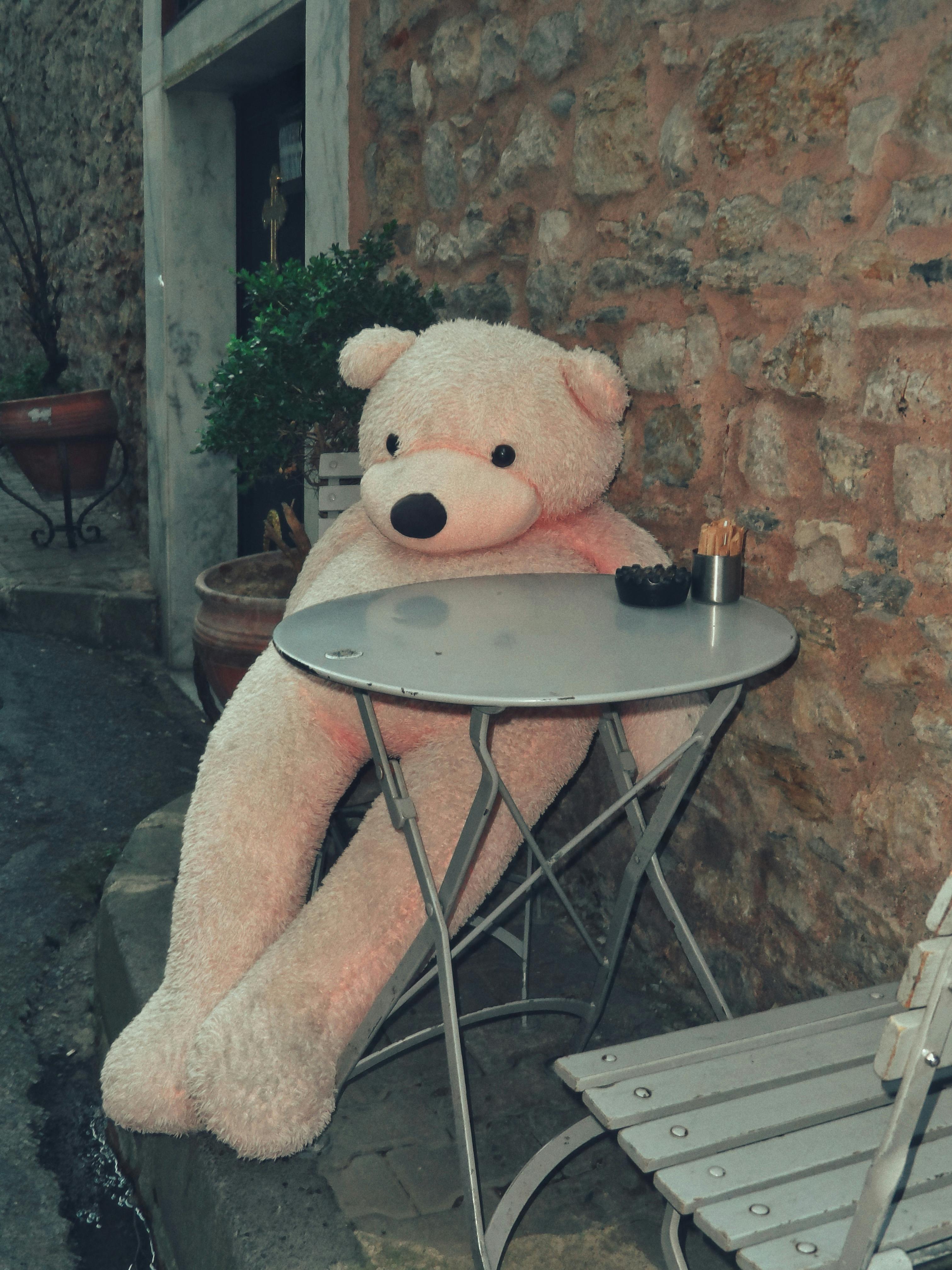 a big teddy bear sitting on a chair outside of a building