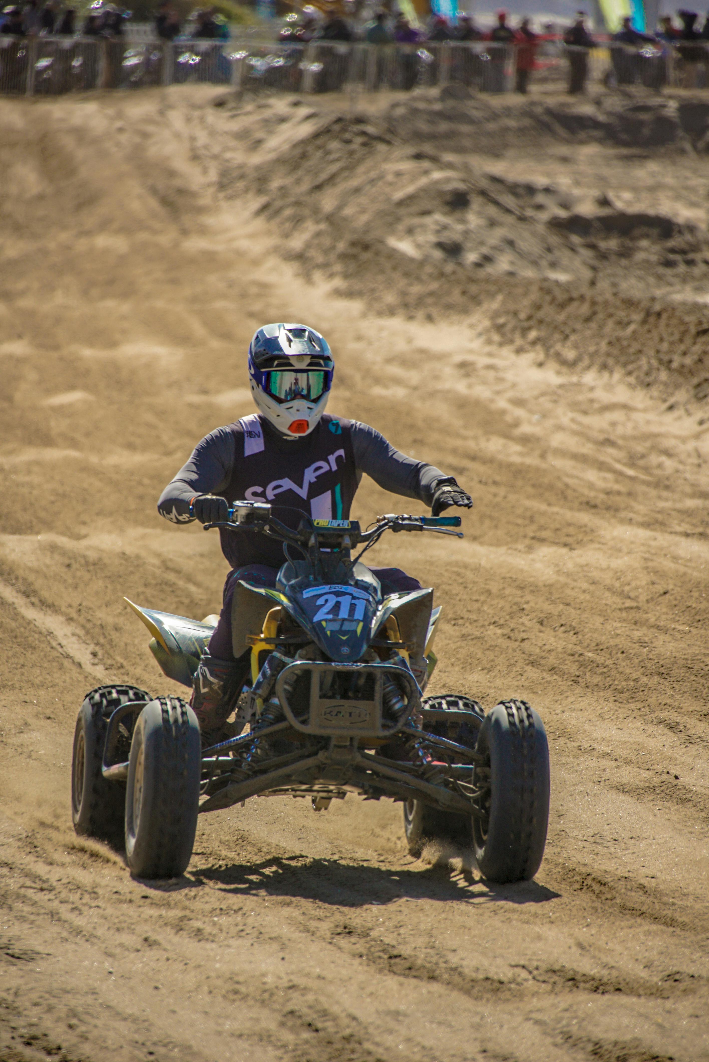 Action-packed scene of a rider racing a quad bike through sandy terrain during the day.