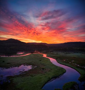 A breathtaking sunset over a winding river in Tell, WI, showcasing vibrant skies.