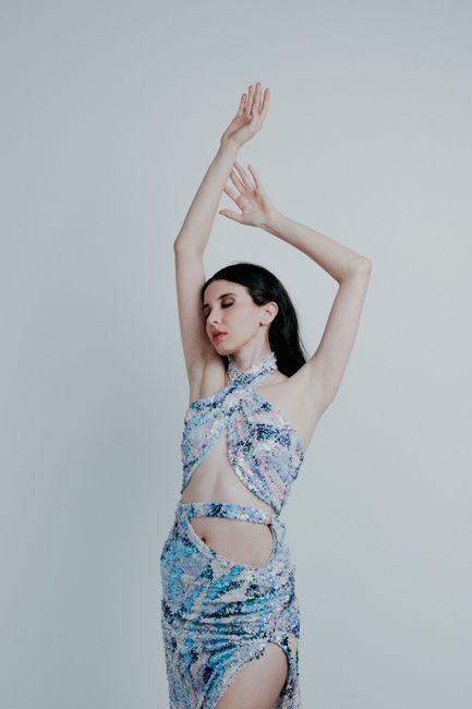 Stylish woman in a colorful dress posing with elegance in a studio setting.