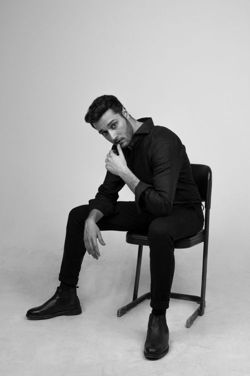 Free Elegant portrait of a man posing on a chair in a studio setting. Stock Photo