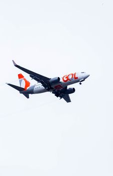 A commercial airliner flying against a bright white sky, showcasing aviation travel dynamics.