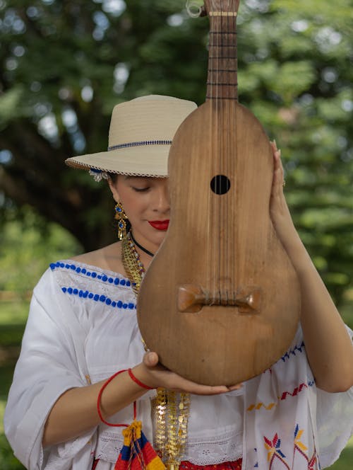Woman in Wide Brimmed Hat Holding a Stringed Musical Instrument