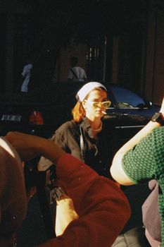 A fashionable woman wearing sunglasses and a bandana captured in an urban environment during the day.