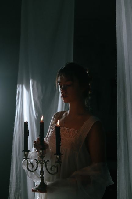 A woman in nightwear holding a candelabra creates a mysterious and moody ambiance.