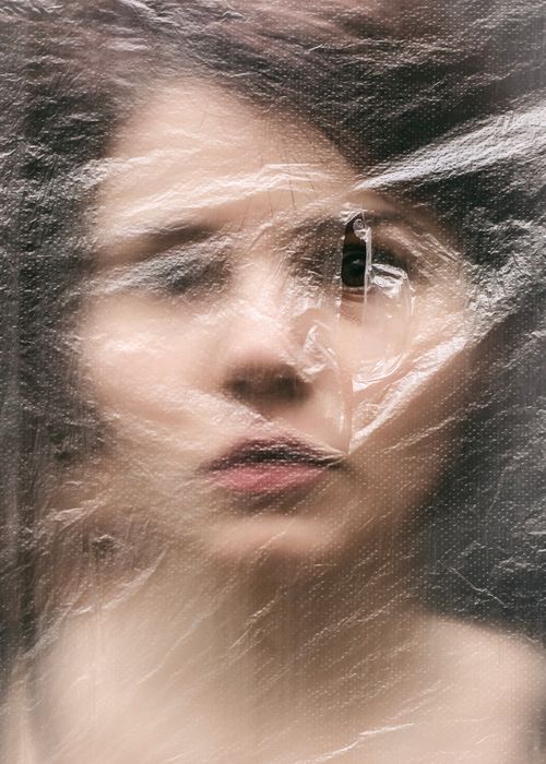 Free Blurred portrait of a woman viewed through plastic foil, creating an abstract effect. Stock Photo