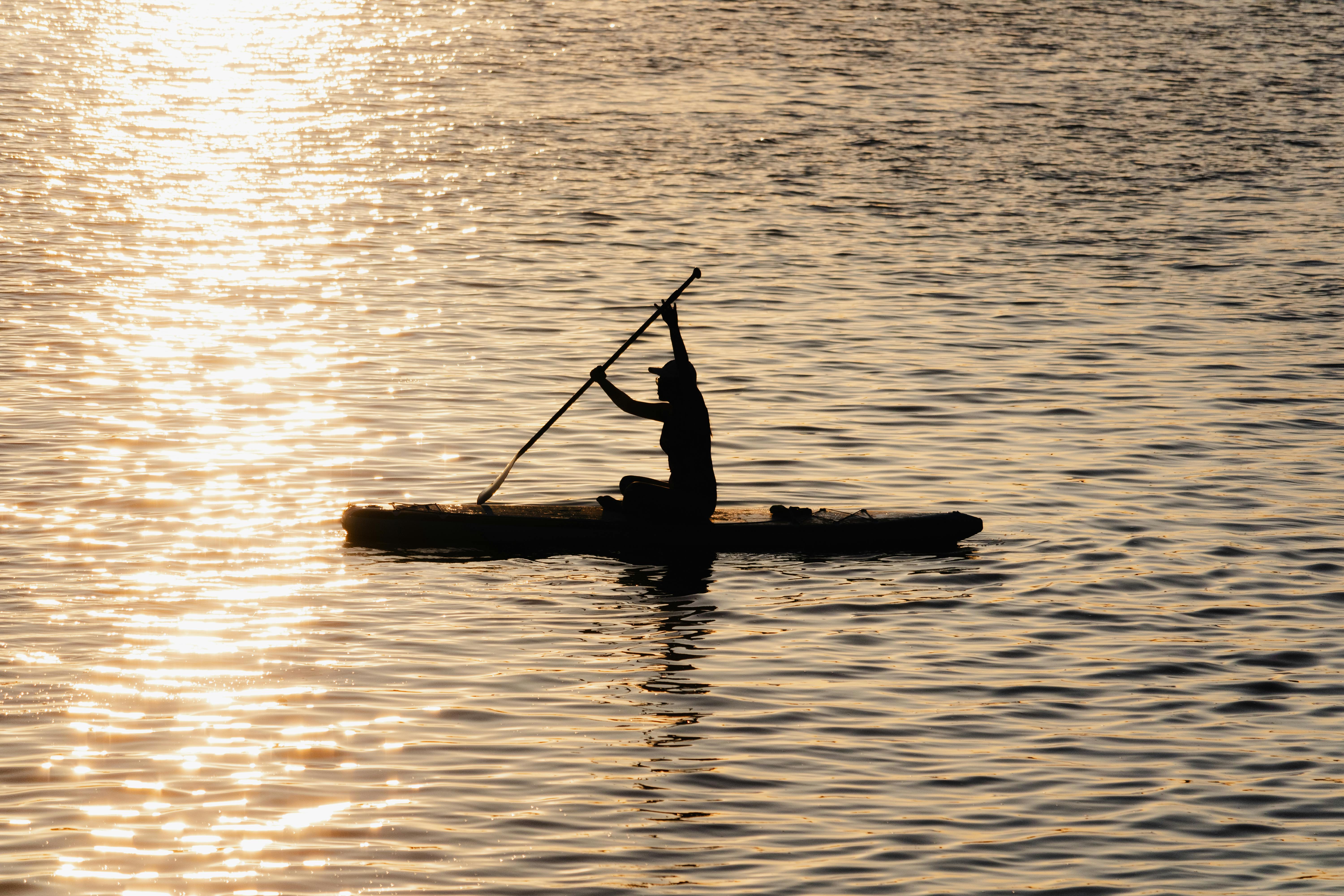 a person paddling in the water at sunset