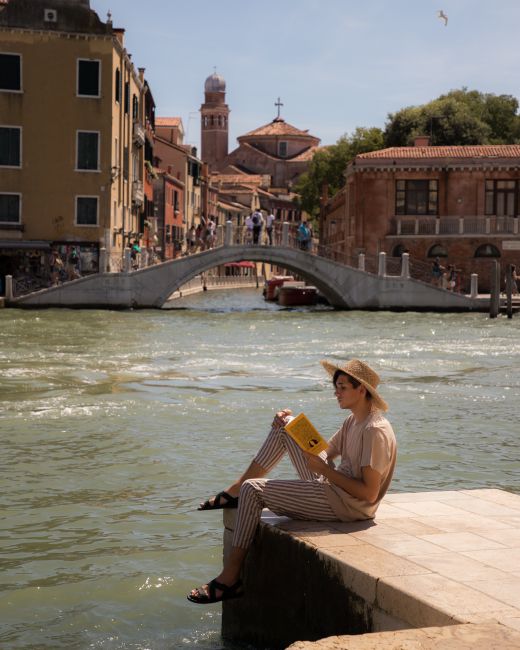 A serene moment by Venice's iconic Canale Grande with a woman reading.