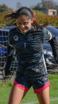 Smiling teenage girl playing soccer in sportswear on a sunny day outdoors.