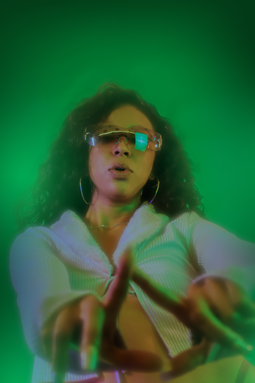 Free Young woman dancing with vibrant lights and a green background in Ciudad de México. Stock Photo
