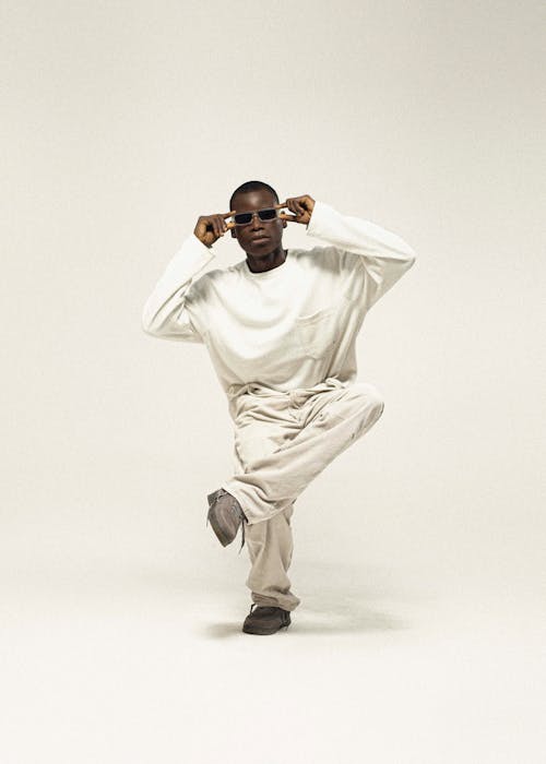 Man with Sunglasses in White Sweatshirt Sitting in Studio