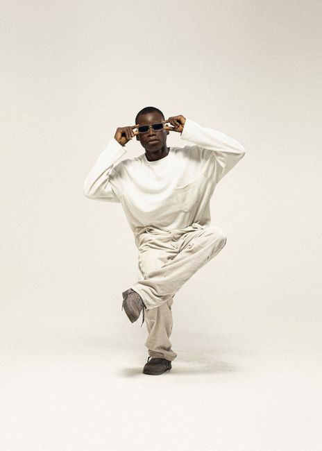A fashionable person posing confidently in a studio with stylish sunglasses.