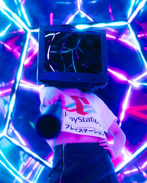 Person Wearing TV on their Head Standing on Bright Neon Background 