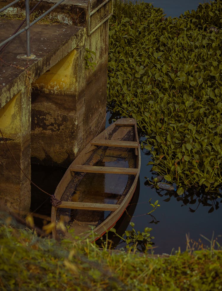 An Old Wooden Canoe Moored To The Pier