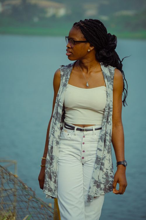 Free Fashionable woman with dreadlocks wearing a white top and eyeglasses by the water. Stock Photo