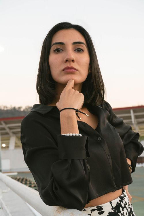 Free A woman in a black blouse poses confidently outdoors, embodying modern fashion and elegance. Stock Photo