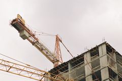 A high-rise building under construction with visible tower cranes and concrete structure.