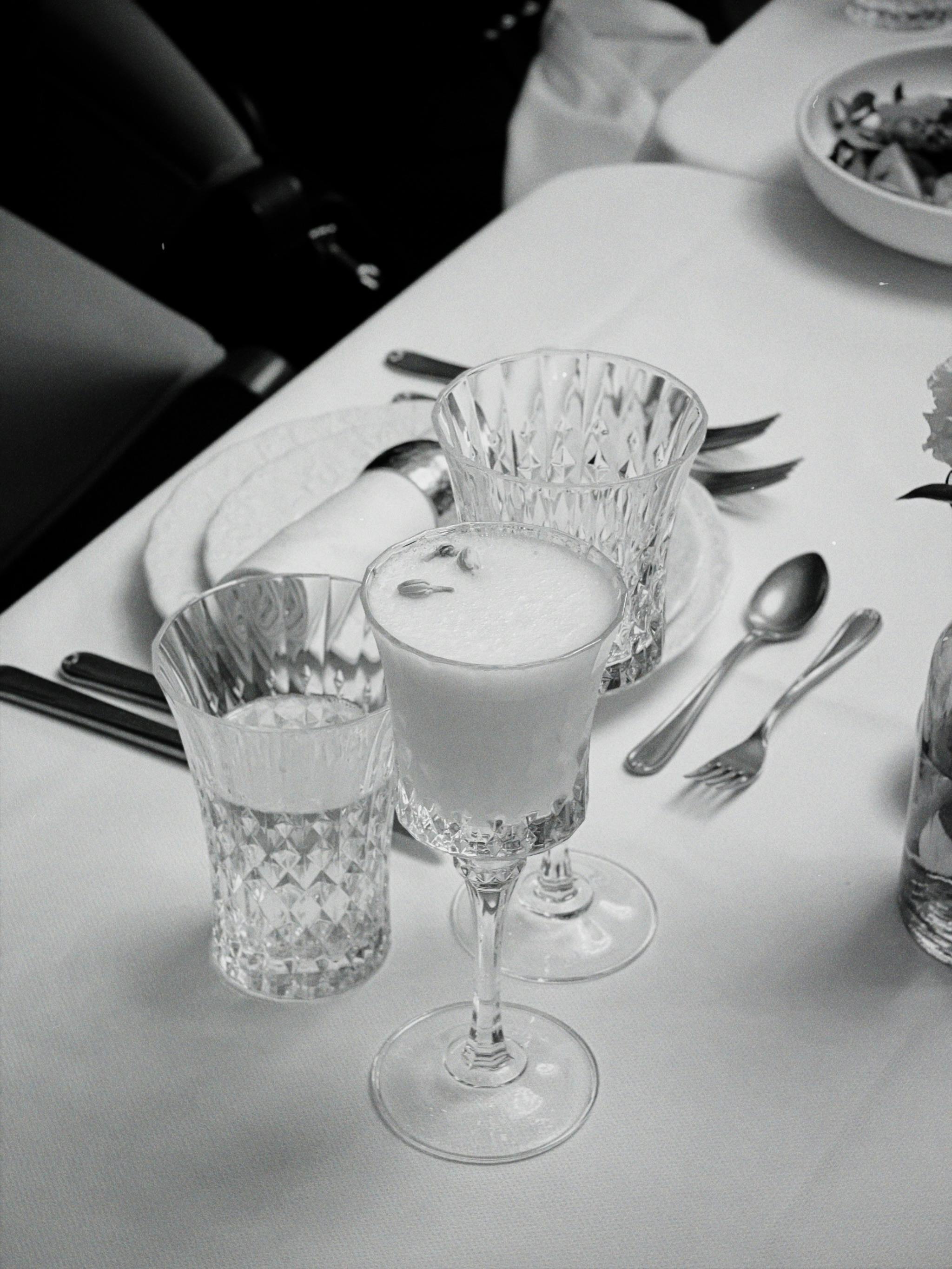 Black and white photo of an elegant table setting with crystal glassware and cutlery, showcasing minimalism and sophistication.