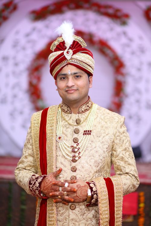 Free Portrait of an Indian man in ornate traditional wedding clothing, smiling at a ceremony. Stock Photo