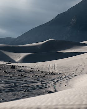 Serene view of sand dunes in Skardu under a dramatic sunset sky, perfect for adventure seekers.
