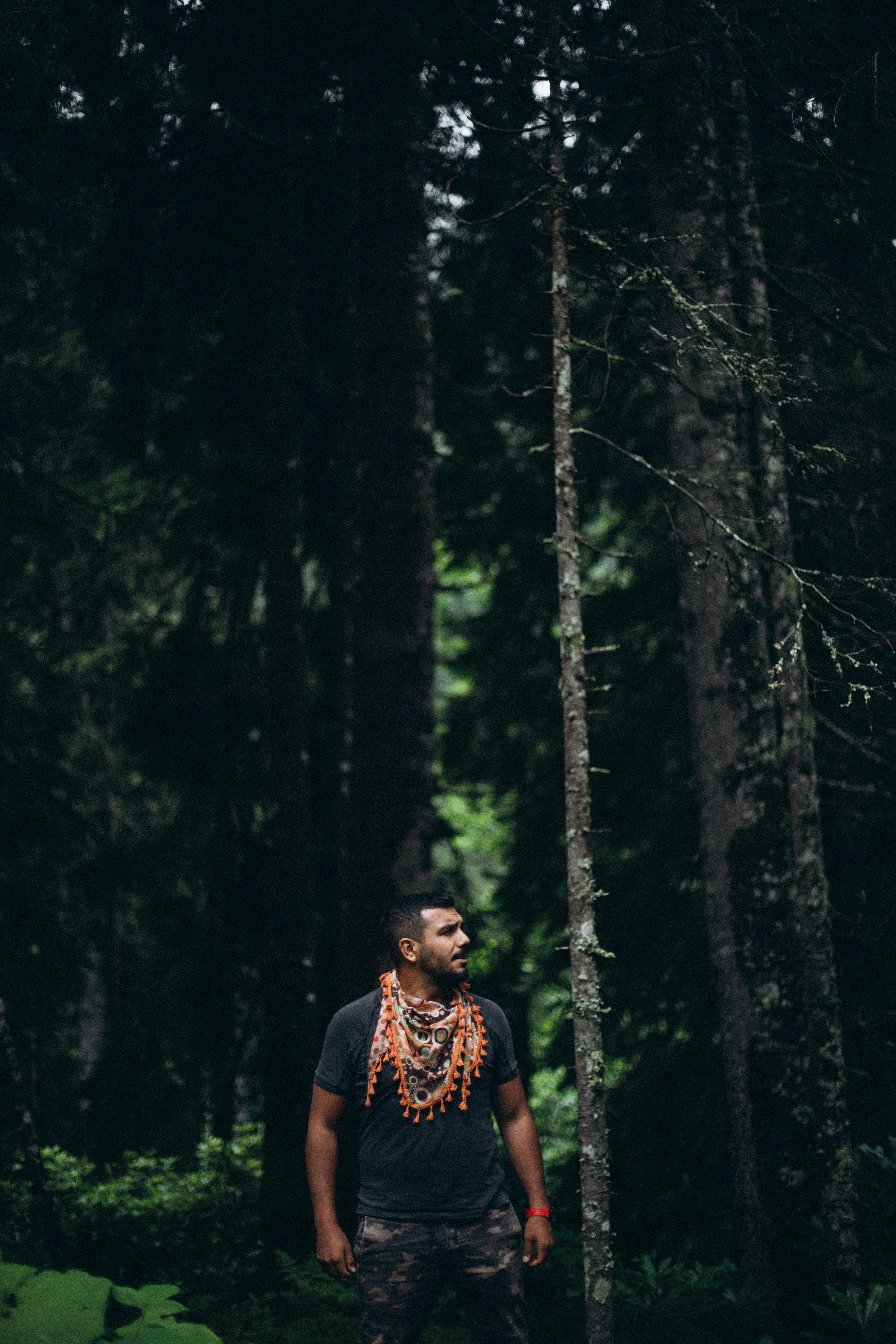 a man standing in the woods wearing a necklace