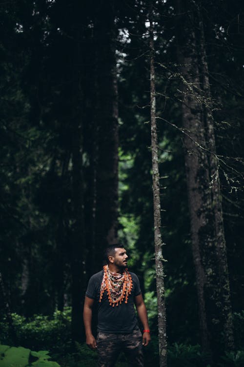 A man standing in the woods wearing a necklace