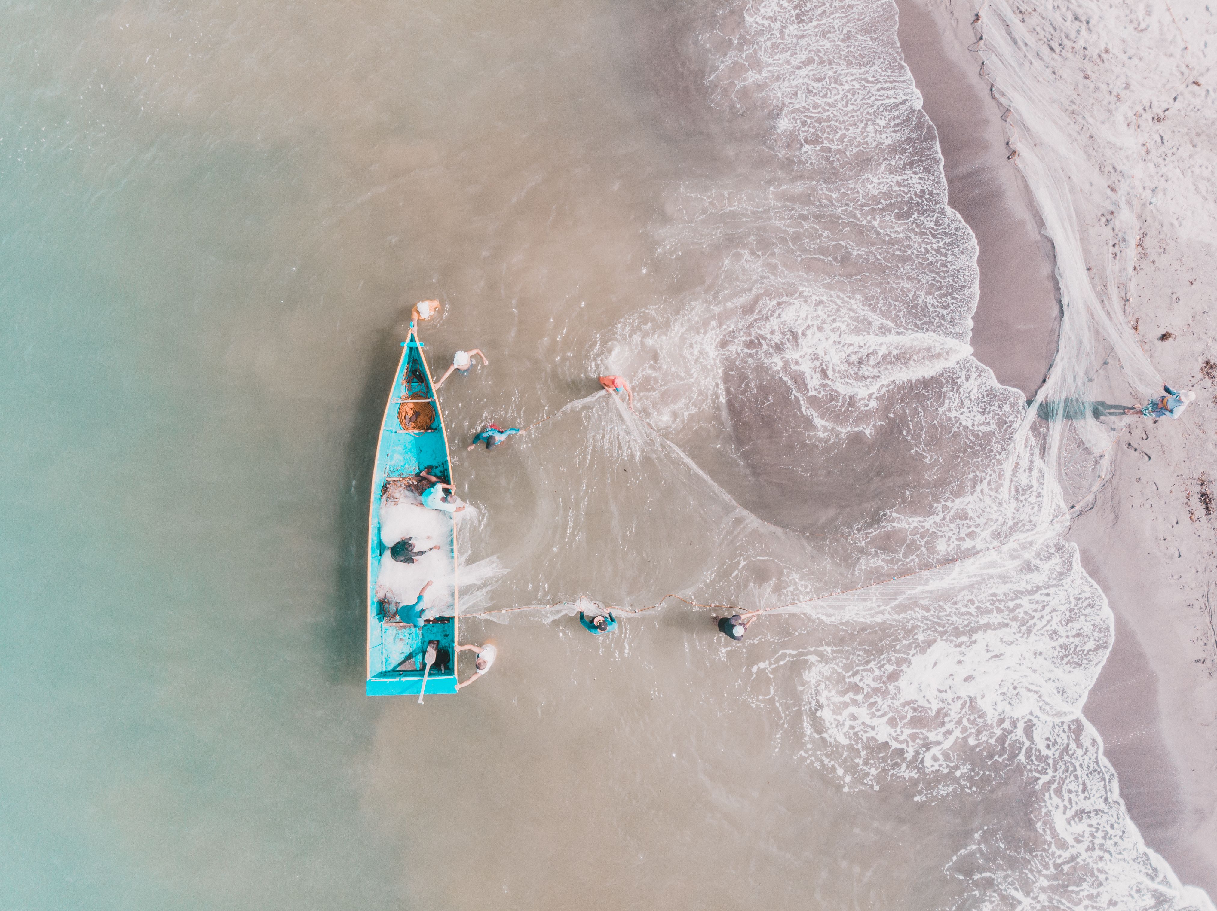 Top-down shot of fishermen working with a boat and net near the shore in the Netherlands.