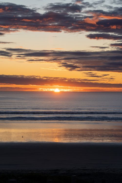Free Stunning sunset view over the ocean in Christchurch, New Zealand with vibrant colors. Stock Photo