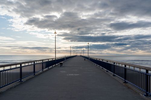 Free A serene view of New Brighton Pier in Christchurch, New Zealand during sunset, showcasing the expansive horizon and calm sea. Stock Photo